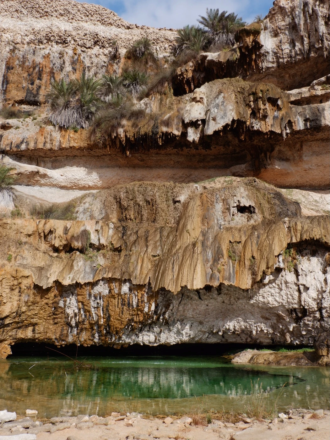Travertine curtain above a pool of blue-green water at Ash Shuwaymiyyah.