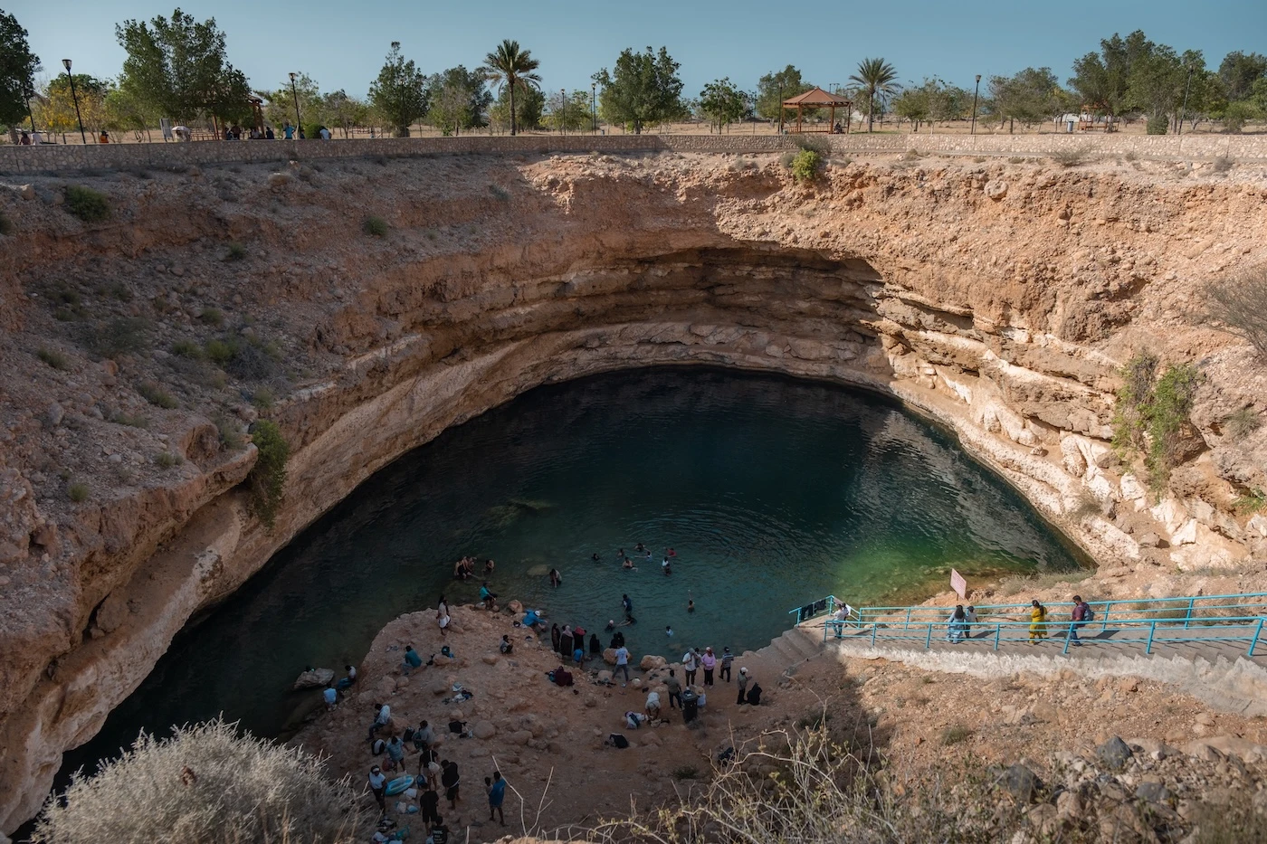 Crowds of visitors enjoying the waters at the Bimmah Sinkhole cenote near Muscat, Oman.