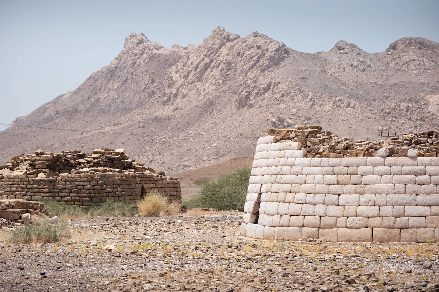 Two partially restored brick-built ancient tomb ruins set in the Hajar Mountains of Oman.