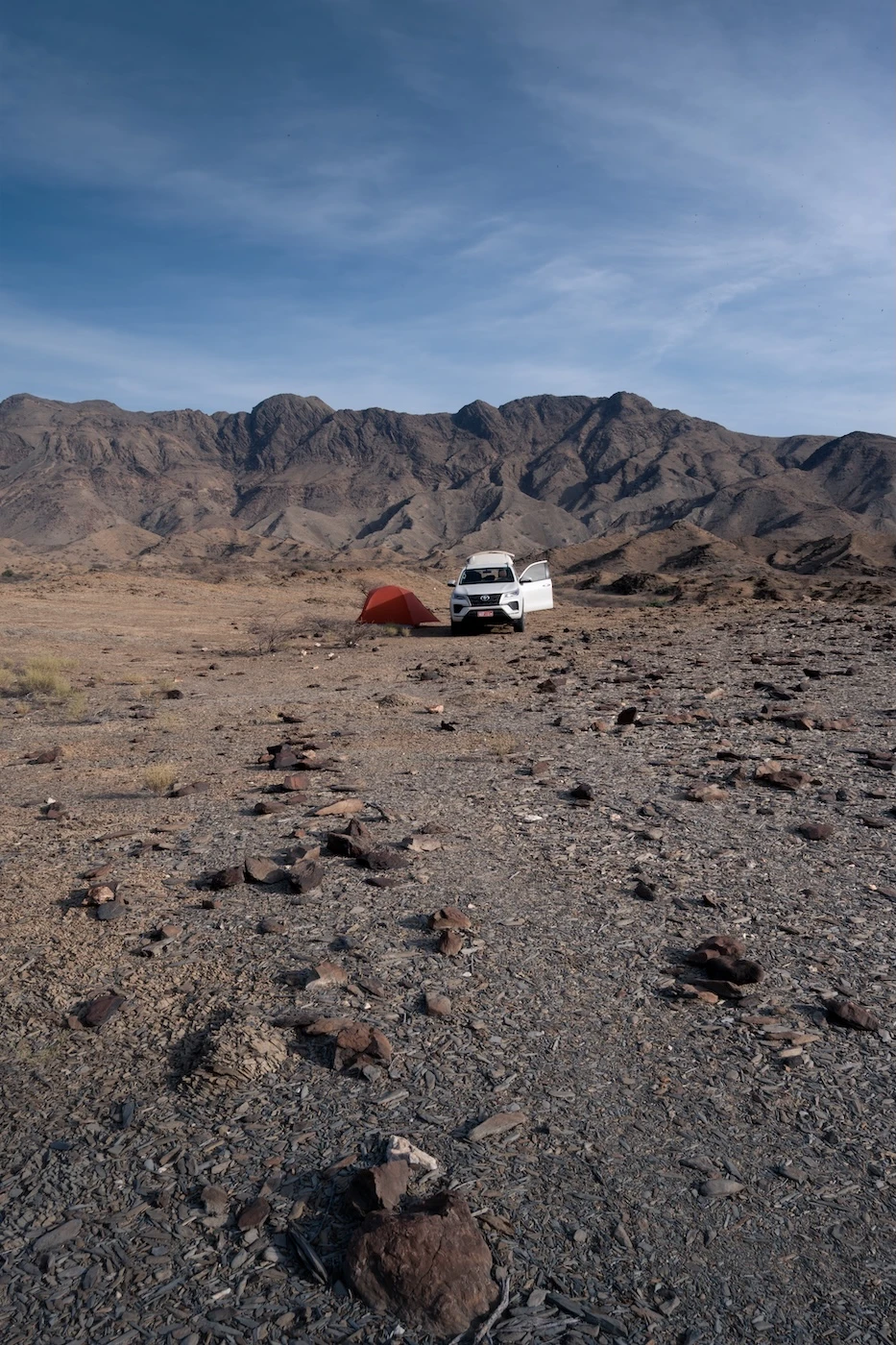 A rental 4WD off-road vehicle at a wild campsite in the Hajar Mountains.