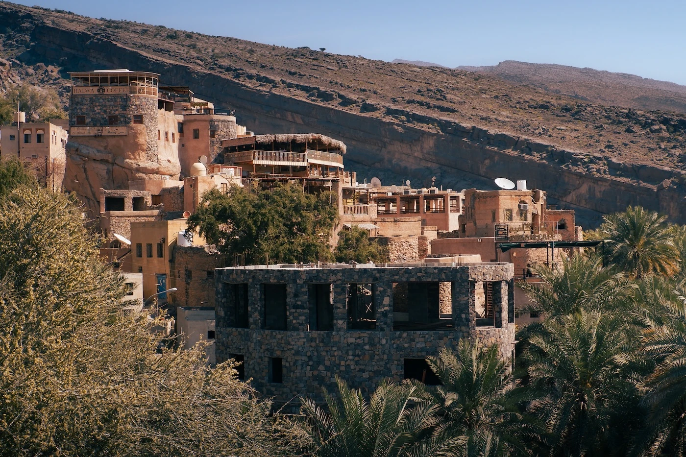 Buildings nestled amongst trees in the hillside at Misfat Al Abriyeen.