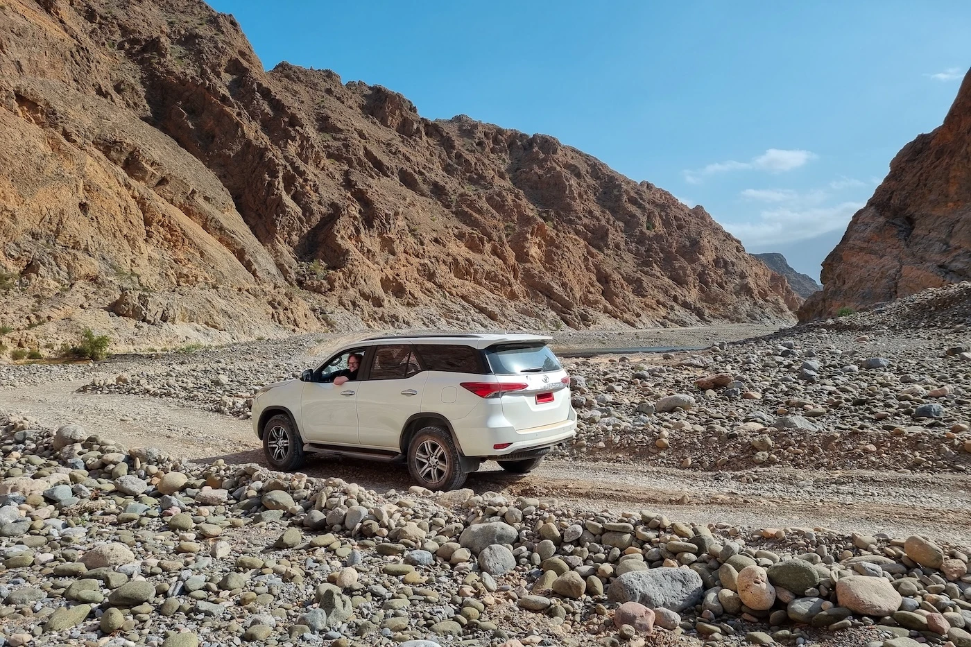 A rental 4WD vehicle driving off-road through unpaved tracks in Wadi Dayqah in Oman.
