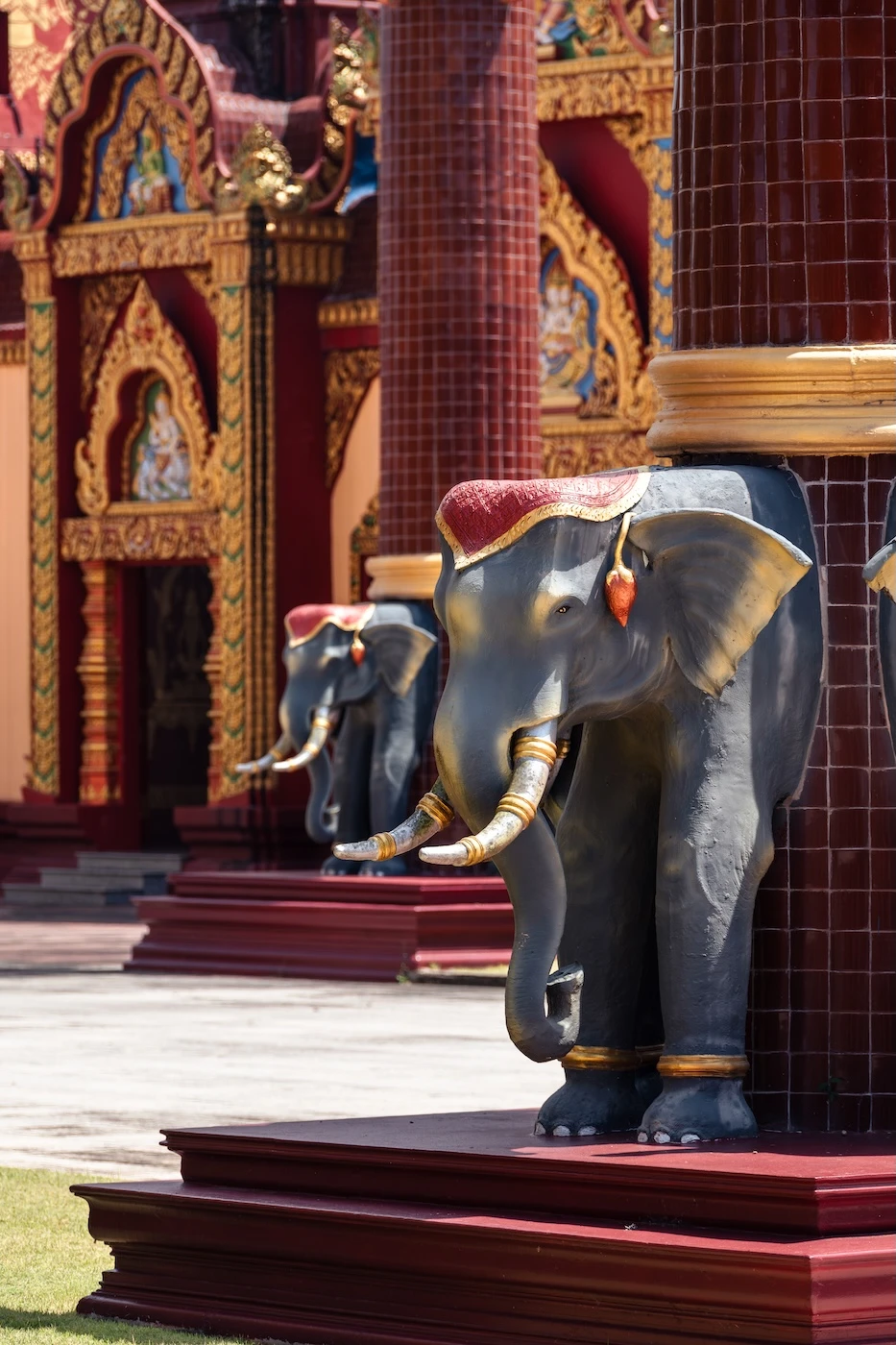 Elephant heads adoring the base of red columns in the temple complex at Wat Bang Thong in Krabi.