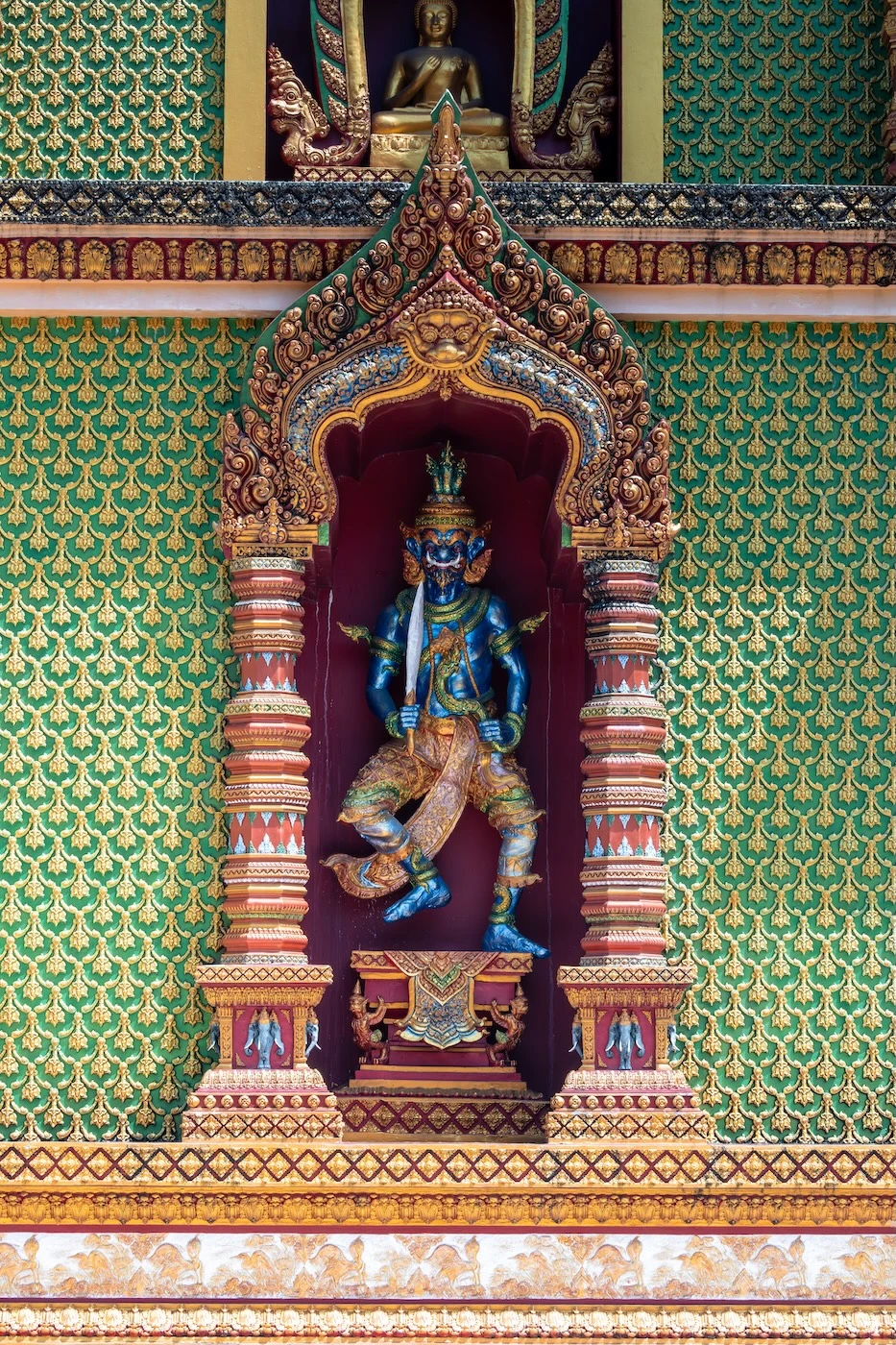 A blue guardian statue brandishing a sword in its right arm, standing guard at Wat Bang Thong temple in Krabi, Thailand.