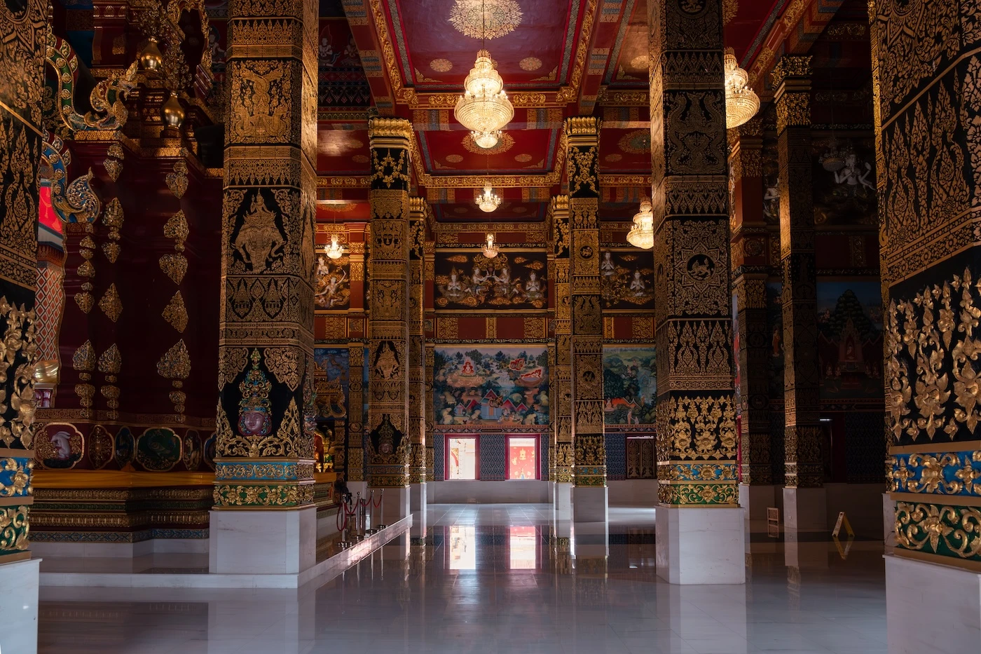 Intricate internal temple decorations in red and gold on the columns, walls and ceilings of Wat bang Thong in Krabi, Thailand.