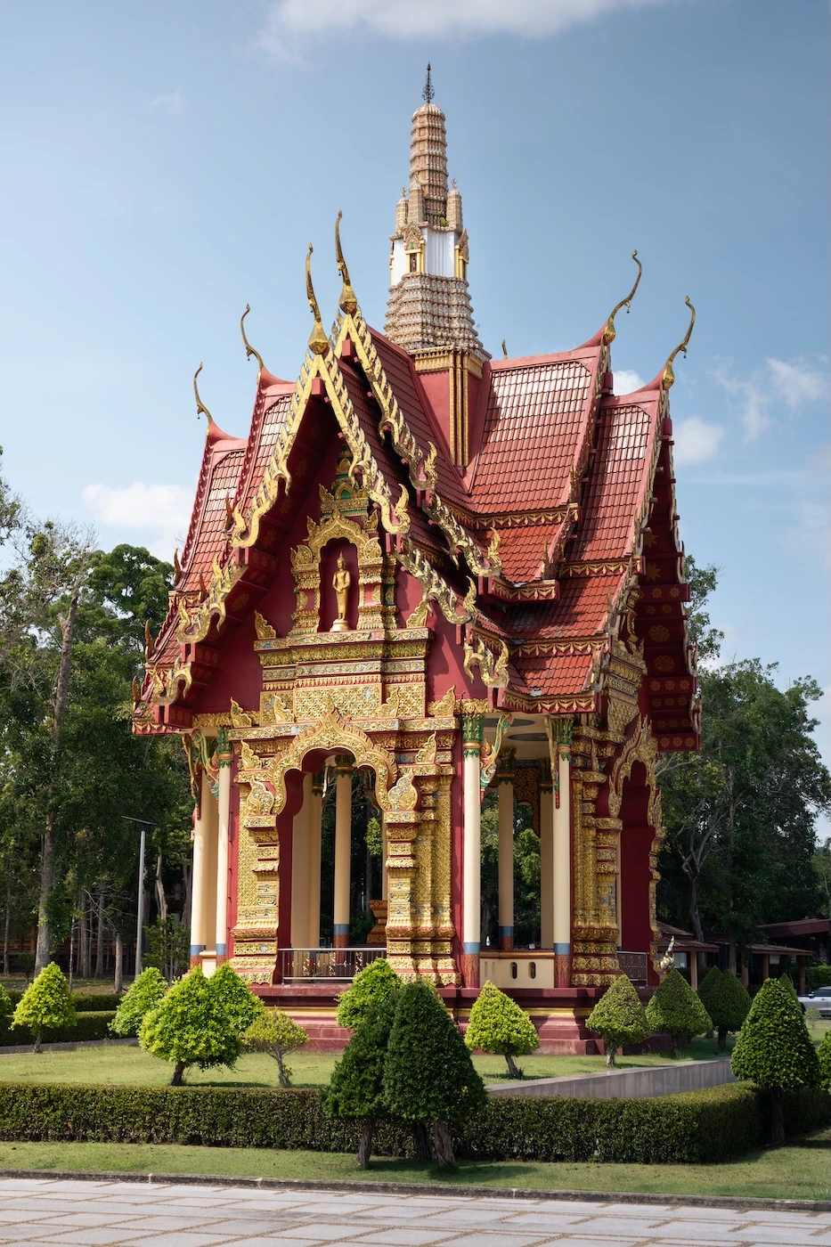 A smaller Thai temple building with red and gold architecture.