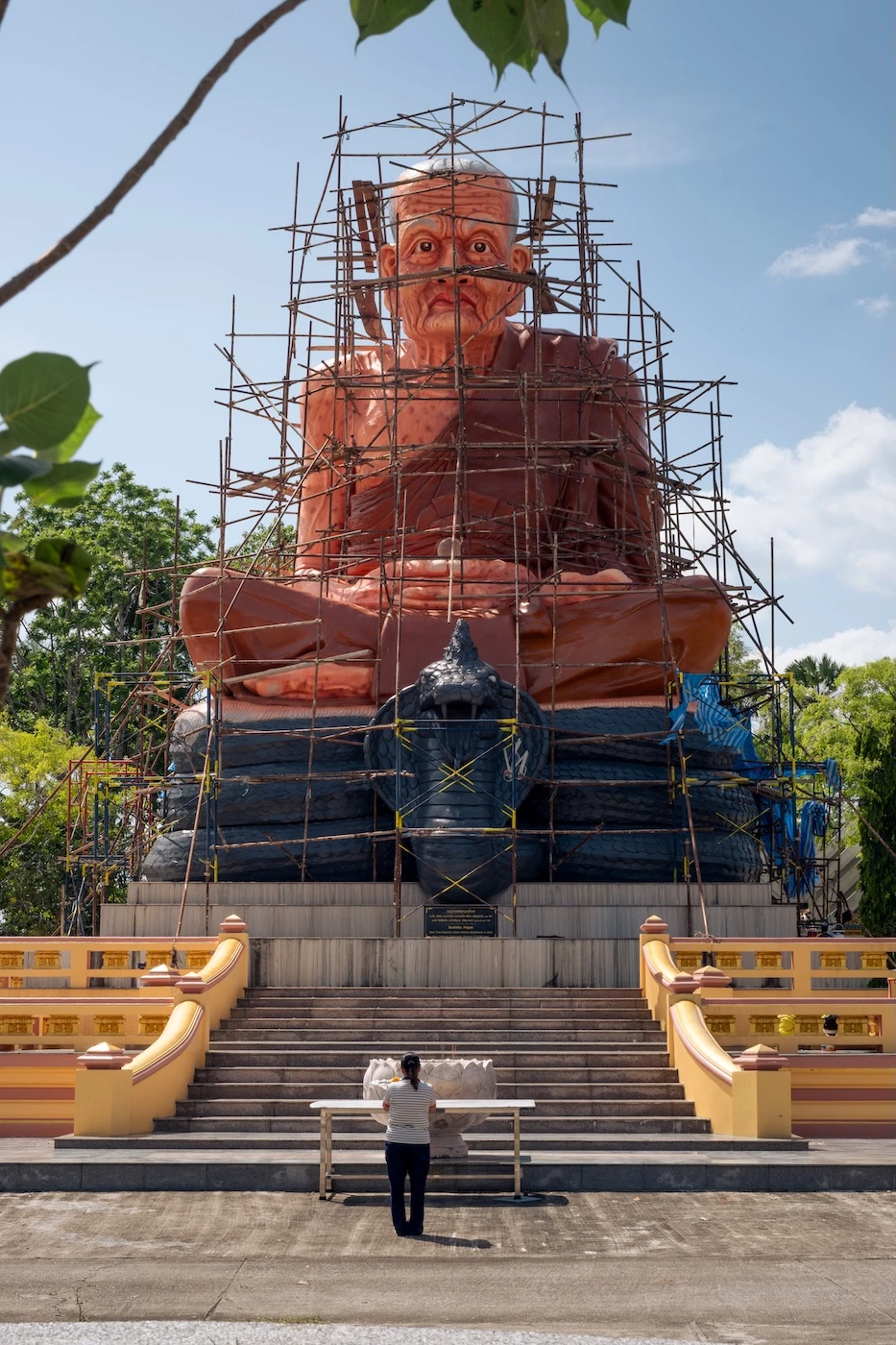 Scaffolding repairs around a giant statue of a monk.